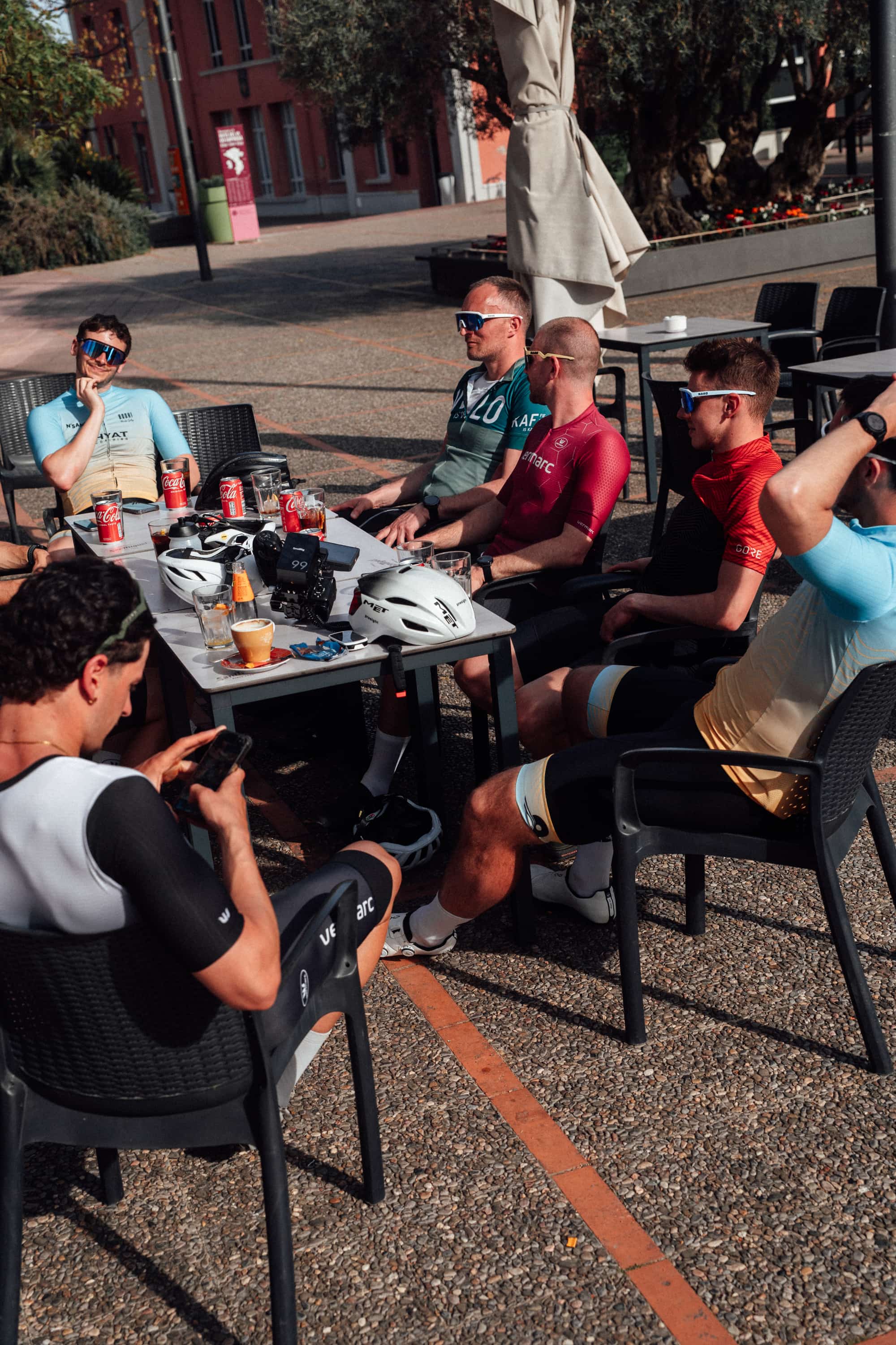 HYTX cyclists at an outdoor café table after a ride, with coffee and helmets on the table